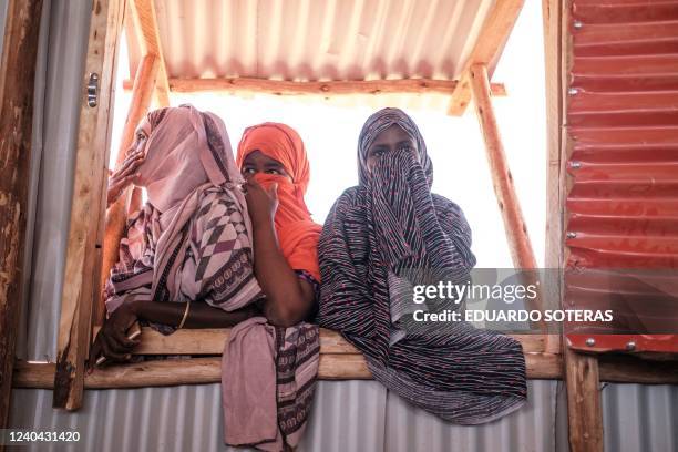 Women look on as they stand in a window in the camp for internally displaced people of Farburo 2 in the village of Adlale, near the city of Gode,...