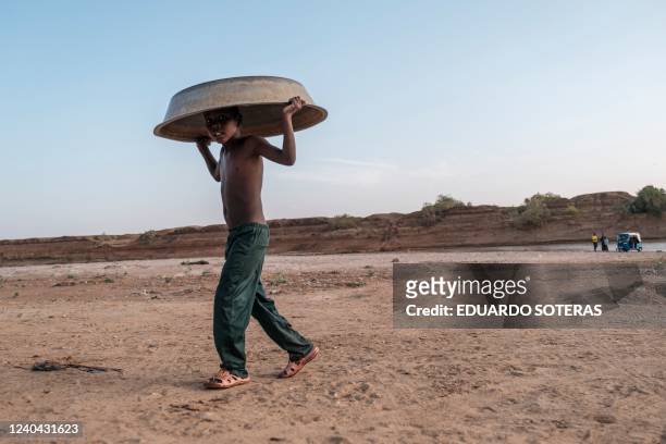 Child carries a water basin in his head near the Shabelle river in the city of Gode, Ethiopia, on April 6, 2022. - The worst drought to hit the Horn...