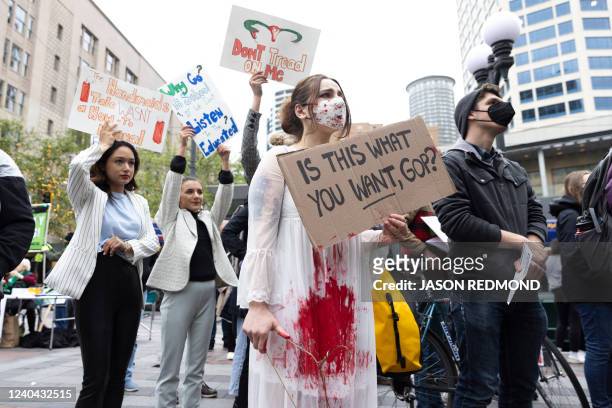 Erica Corbin of Tacoma, wearing a bloody gown, holds a hanger, a symbol of the reproductive rights movement, and a sign that reads "is this what you...