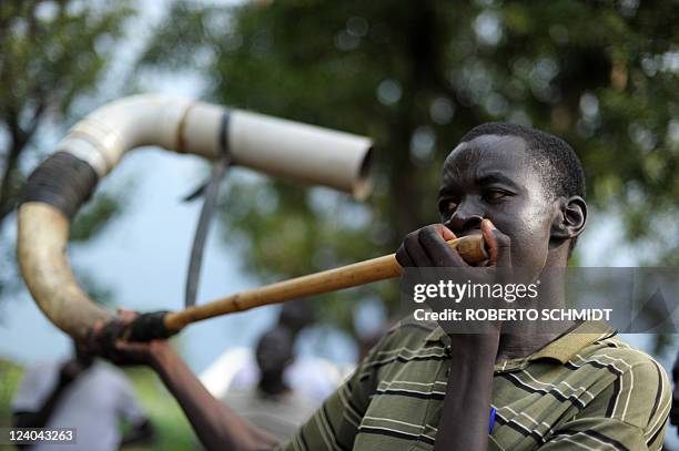 Member of the Mundari ethnic group blows into a horn during a wrestling match in a dusty patch where the tribe brought cattle and sheep for sale in...