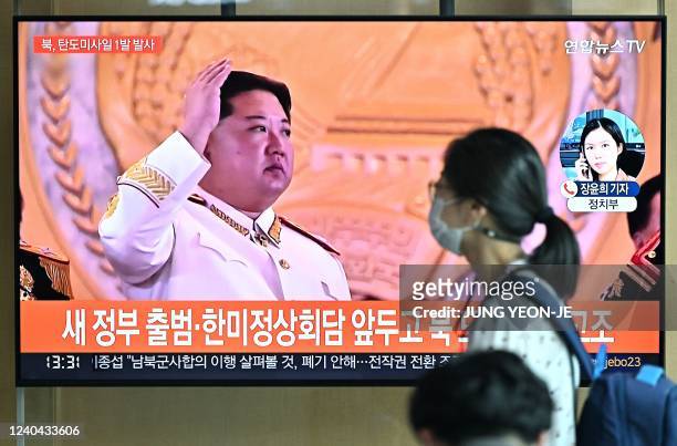 Woman walks past a television screen showing a news broadcast with file footage of North Korean leader Kim Jong Un, at a railway station in Seoul on...