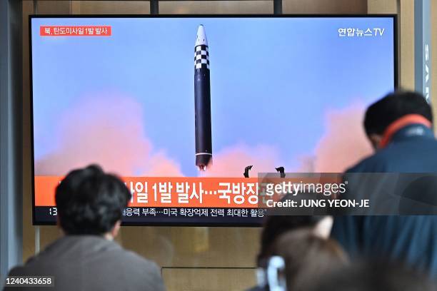 People watch a television screen showing a news broadcast with file footage of a North Korean missile test, at a railway station in Seoul on May 4,...
