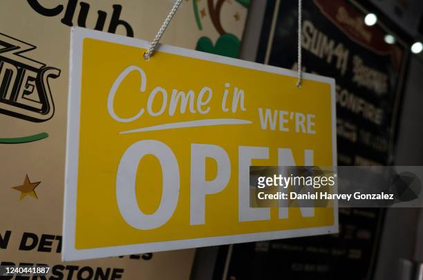 Bright yellow sign that reads "come in, we're open" welcomes potential customers into a record shop in the city centre on 30th April, 2022 in Leeds,...