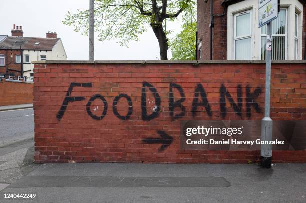 Wall covered by bold, black graffiti that points towards a local food bank in Harehills, one of the most deprived areas of Leeds, as charity the...