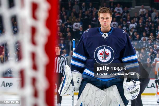 Goaltender Eric Comrie of the Winnipeg Jets looks on prior to NHL action against the Philadelphia Flyers at Canada Life Centre on April 27, 2022 in...