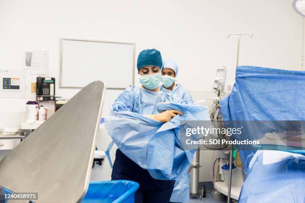 después de la operación, el médico se quita la bata quirúrgica - hospital gown fotografías e imágenes de stock