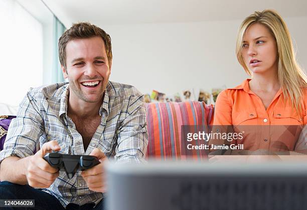 girlfriend mat at boyfriend playing video game - couple relationship difficulties stock pictures, royalty-free photos & images