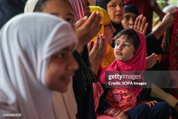 Kashmiri Muslim girl looks while women offer prayers during Eid-al-Fitr prayers at a local mosque in Srinagar. Eid-al-Fitr festival marks the end of...