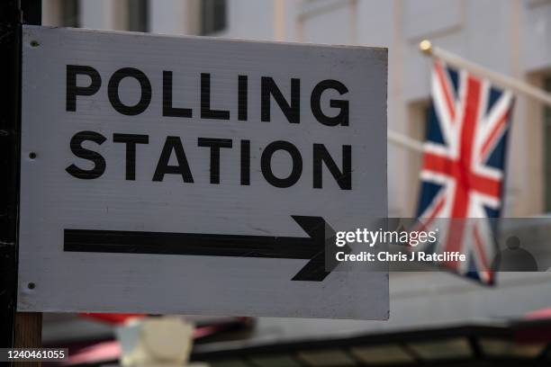 Union Jack flag flies behind a sign pointing to a polling station on May 5, 2022 in London, United Kingdom. Voters go to the polls in the local...