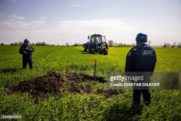 Members of a demining team of the State Emergency Service of Ukraine prepare to destroy an unexploded missile remaining near the village of...