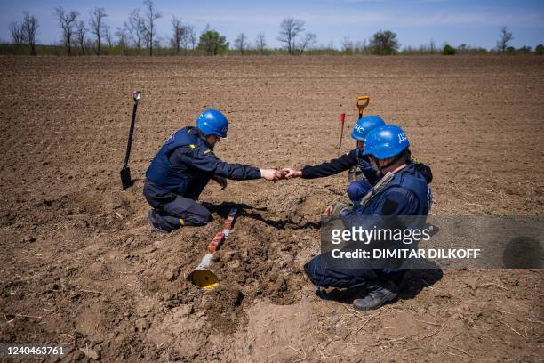 Members of a demining team of the State Emergency Service of Ukraine work to destroy an unexploded missile remaining near the village of Hryhorivka,...