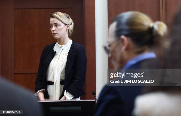 Actress Amber Heard testifies as US actor Johnny Depp looks on during a defamation trial at the Fairfax County Circuit Courthouse in Fairfax,...