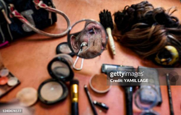 Victoria, a Cuban transgender woman, puts on makeup at her house in Havana, on April 29, 2022. - Cuban transgenders hope that the Code of Families,...