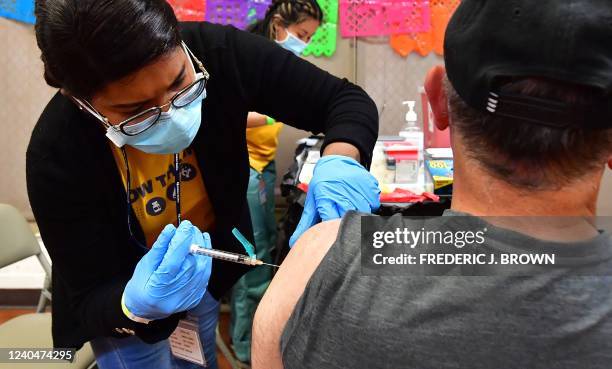 Registered Nurse Mariam Salaam administers the Pfizer booster shot at a Covid vaccination and testing site decorated for Cinco de Mayo at Ted Watkins...