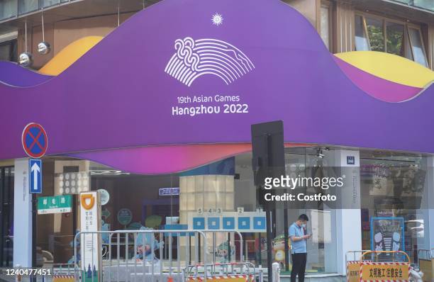 People walk past a concession store for the 2022 Asian Games in Hangzhou, East China's Zhejiang Province, May 6, 2022. On May 6 the Director general...
