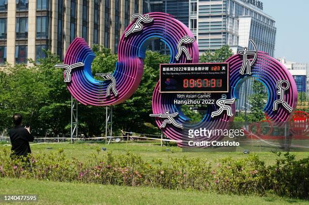 Citizens take photos of a commemorative plaque marking the countdown to the 2022 Hangzhou Asian Games in downtown Hangzhou, East China's Zhejiang...