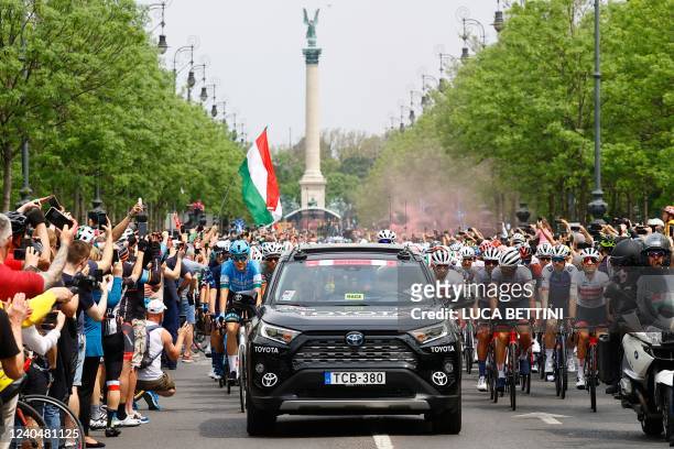 Spectators cheer as riders gather behind the race's director car prior to the start of the first stage of the Giro d'Italia 2022 cycling race, 195...