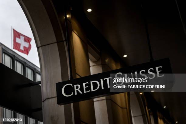 This photograph taken on May 6, 2022 shows a sign of Switzerland's second largest bank Credit Suisse on a branch's building next to a Swiss flag in...