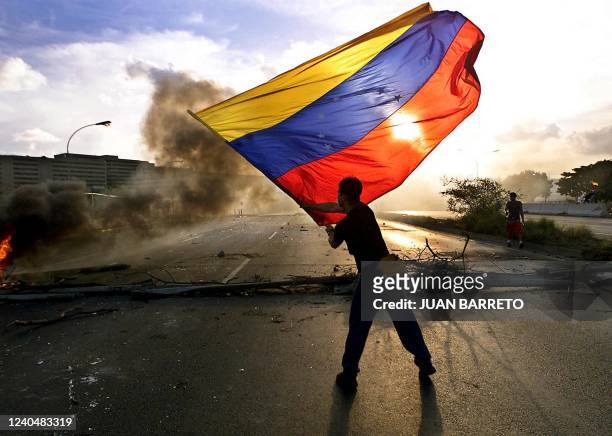 An opponent of Venezuelan President Hugo Chavez waves the Venezuelan national flag during a protest 03 December 2002 in Caracas. Police fired tear...