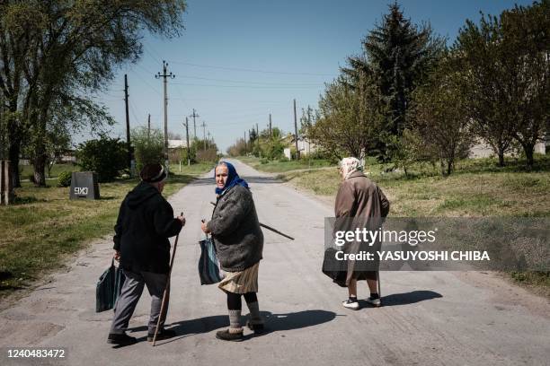 Elderly women leave after receiving their pension from a postal delivery van that reached the frontline despite the ongoing conflict as the sound of...