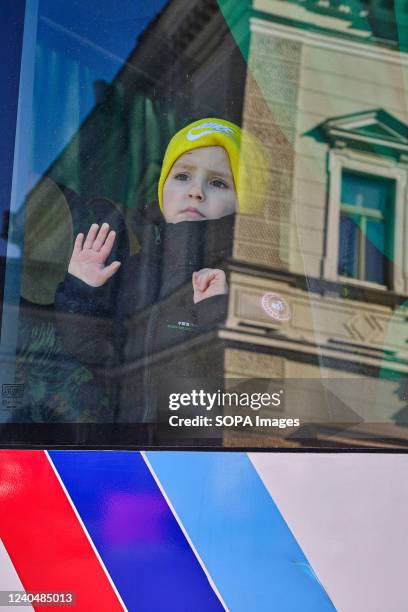 Ukrainian boy with a blank stare is seen on the bus window bound for Warsaw. The war in Ukraine has forced millions of Ukrainians to leave their...