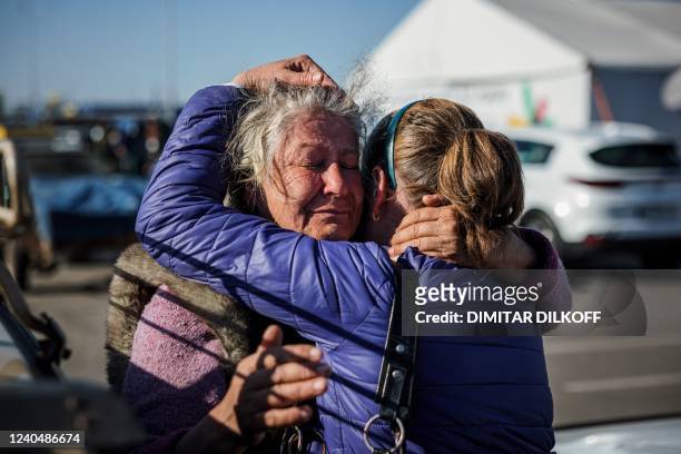 Olga Babich hugs her daughter after arriving from the village of Mali Shcherbaky at a registration and processing area for internally displaced...