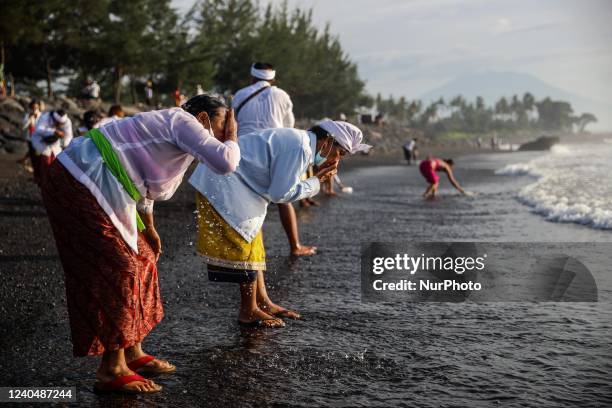 Balinese Hindu devotees wash their faces with sea water as they pray during the Melasti, a purification ceremony ahead of Nyepi at a beach in Bali,...