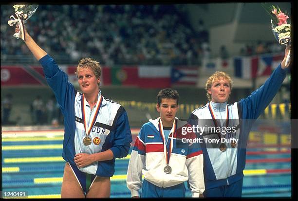 KRISTIN OTTO OF EAST GERMANY CELEBRATES RECEIVING HER GOLD MEDAL ALONG WITH KISZTINA EGERSZEGI OF HUNGARY AND CORNELIA SIRCH OF EAST GERMANY AFTER...