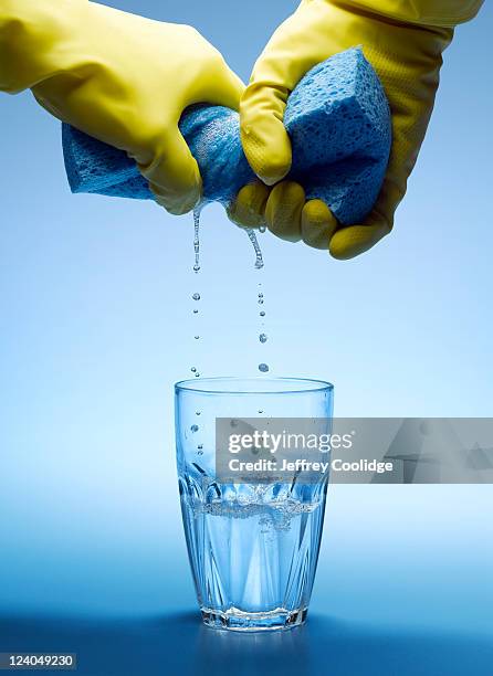 wringing sponge into water glass - spugna per le pulizie foto e immagini stock