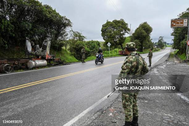 Soldiers stand guard next to a truck burnt by members of the Clan del Golfo drug cartel, on a road near Yarumal, Antioquia department, Colombia, on...
