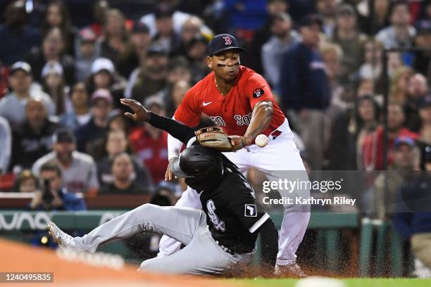 Tim Anderson of the Chicago White Sox safely slides into third base as Rafael Devers of the Boston Red Sox bobbles the ball in the third inning at...