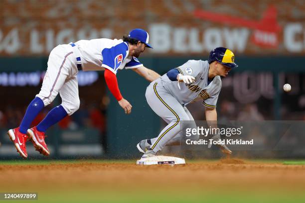 Luis Urias of the Milwaukee Brewers slides into second base safely as Dansby Swanson of the Atlanta Braves has the ball thrown away from him during...