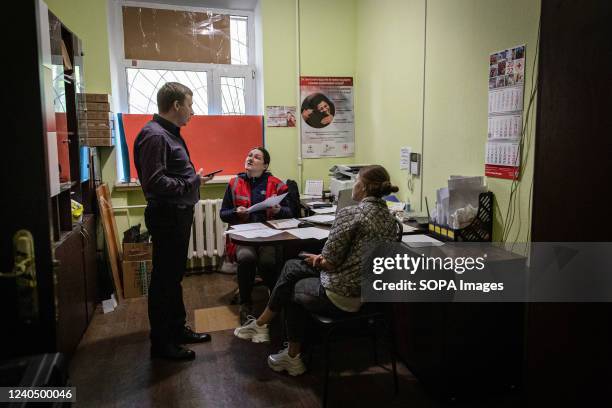 The staff helps a husband and wife fill out the application form for medicine they need in the Red Cross office located in Kharkiv. Despite constant...