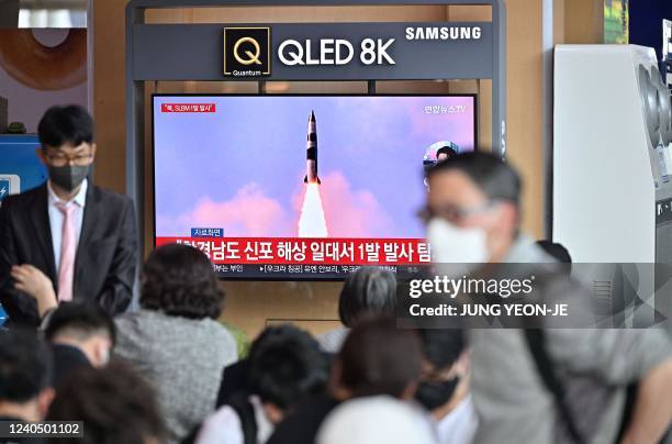 People watch a television screen showing a news broadcast with file footage of a North Korean missile test, at a railway station in Seoul on May 7...