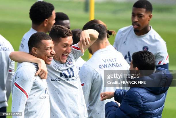 Paris Saint-Germain's French forward Kylian Mbappe jokes with Paris Saint-Germain's Spanish midfielder Ander Herrera during a training session at the...