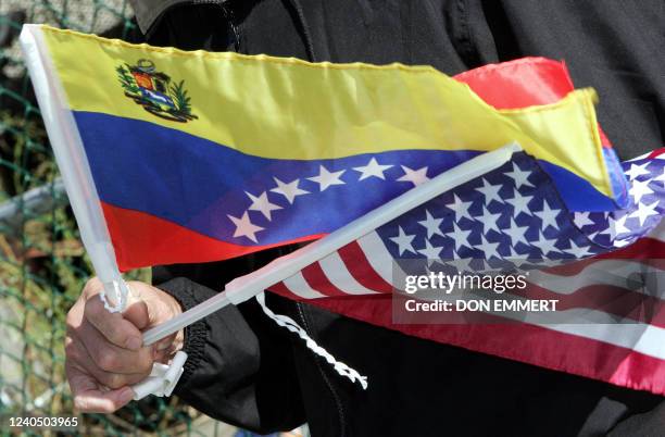 Neighbors of a cooperative apartment building, flying flags of Venezuela and the US, listen to political speeches as low cost heating oil was being...