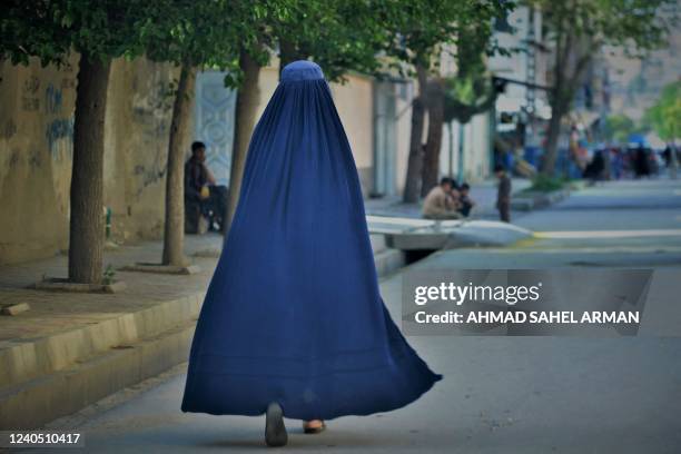 Burqa-clad woman walks along a street in Kabul on May 7, 2022. - The Taliban on May 7 imposed some of the harshest restrictions on Afghanistan's...