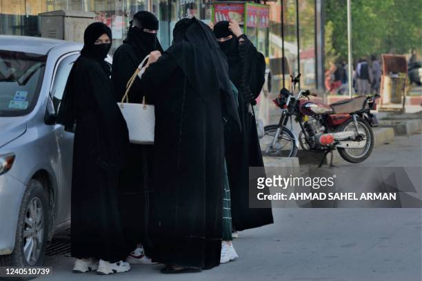 Women wearing Niqab garments stand along a street in Kabul on May 7, 2022. - The Taliban on May 7 imposed some of the harshest restrictions on...