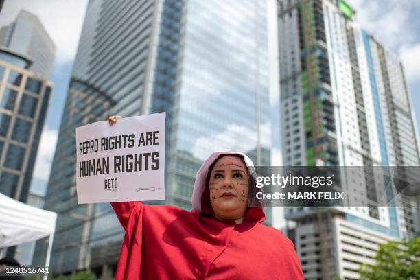 Woman holds a sign while dressed as a character from The Handmaids Tale during A Texas Rally for Abortion Rights in Houston, Texas, on May 7, 2022. -...