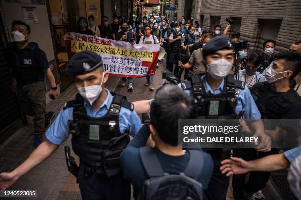 Police usher the media as three members of the League of Social Democrats march on a street during a protest against the selection process of the...