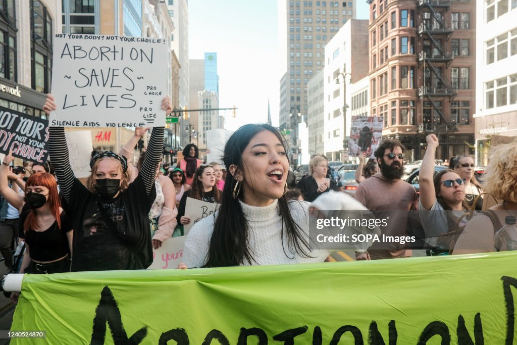 Protesters hold placards, chant, and march through downtown...