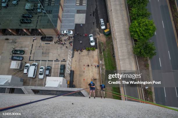 From left, Arlington County Board Member Matt de Ferranti and Chairman of the Fairfax County Board of Supervisors Jeff McKay rappel from the roof of...