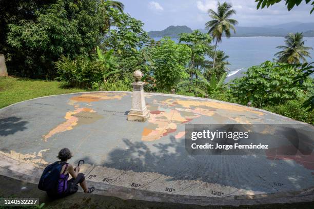 Woman sitting in front of the monument that marks the equator on the island of Las Rolas.