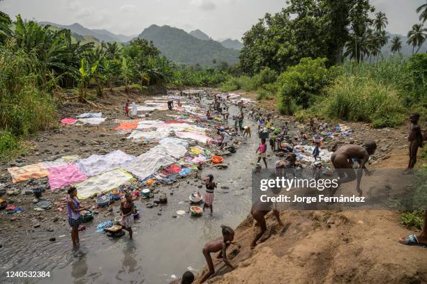 Women and girls washing clothes in the river near the city of Neves while some children play and bathe naked.