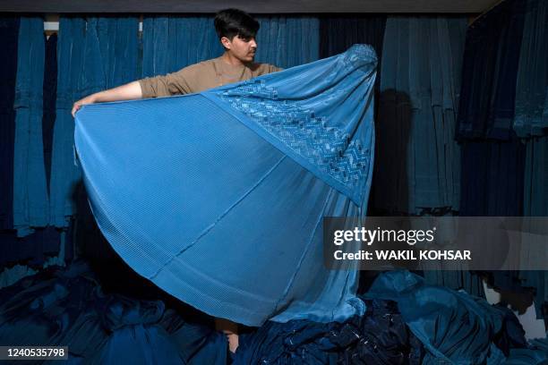 An Afghan vendor displays a burqa at his shop at Mandawi market in Kabul on May 8, 2022. - The Taliban on May 7 imposed some of the harshest...