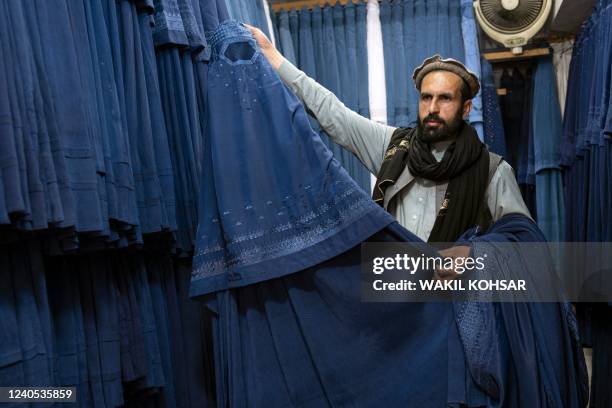 An Afghan vendor displays a burqa at his shop at Mandawi market in Kabul on May 8, 2022. - The Taliban on May 7 imposed some of the harshest...