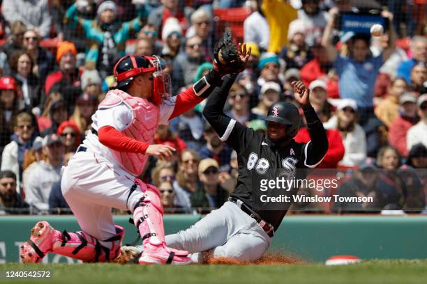 Luis Robert of the Chicago White Sox beats the throw home catcher Christian Vazquez of the Boston Red Sox to score a run during the third inning at...