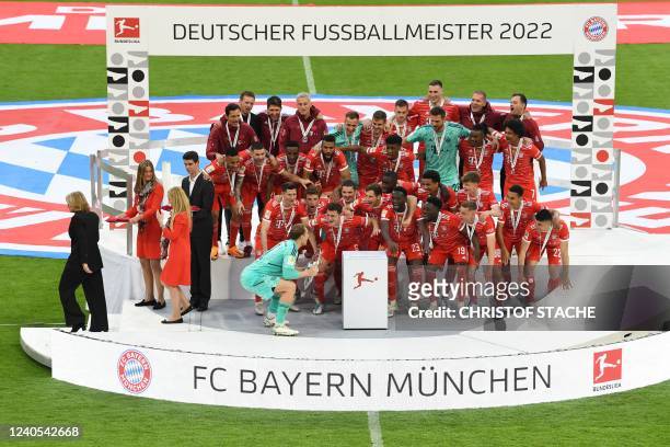 Bayern Munich players celebrate with the trophy as the Manaing Director of the German Football League Donata Hopfen walks away after the German first...