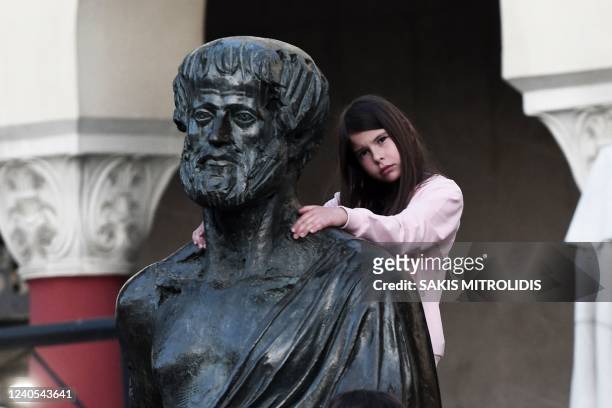 Girl climbs on a statue of Aristotle during an anti-war rally concert in solidarity with Ukraine, organised by the Union of Musicians of Northern...