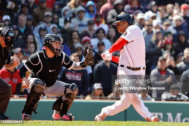 Rafael Devers of the Boston Red Sox looks back to see the ball in the glove of catcher Reese McGuire of the Chicago White Sox after striking out...